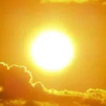 Aurinko paistaa oranssilla taivaalla pilvien yllä