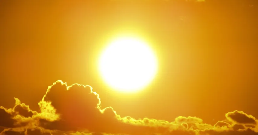 Aurinko paistaa oranssilla taivaalla pilvien yllä