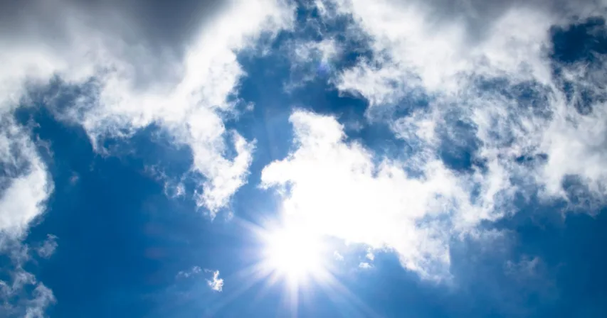 Aurinko paistaa pilvien lomasta sinisellä taivaalla