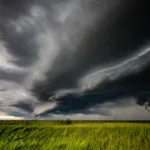 Tumma myrskypilvi vihreän pellon yllä